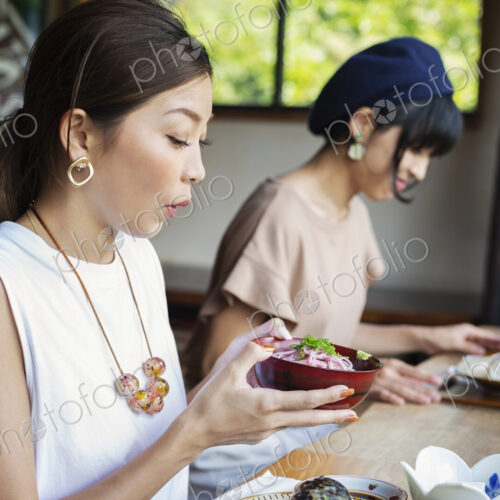 Two Japanese women sitting at a table in a Japanese restaurant, eating. Two Japanese women sitting at a table in a Japanese restaurant, eating.