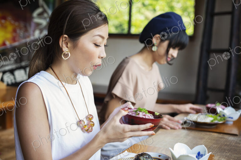 Two Japanese women sitting at a table in a Japanese restaurant, eating.
