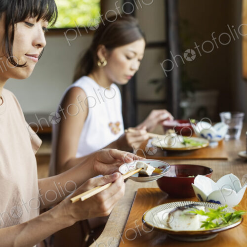 Two Japanese women sitting at a table in a Japanese restaurant, eating. Two Japanese women sitting at a table in a Japanese restaurant, eating.