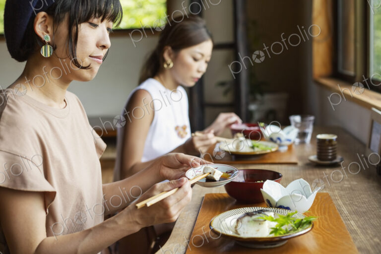 Two Japanese women sitting at a table in a Japanese restaurant, eating.