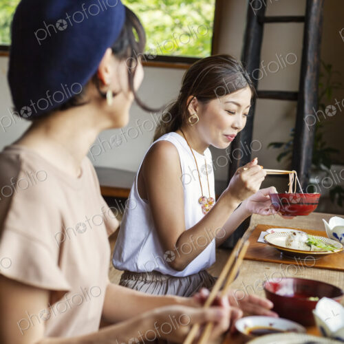 Two Japanese women sitting at a table in a Japanese restaurant, eating. Two Japanese women sitting at a table in a Japanese restaurant, eating.