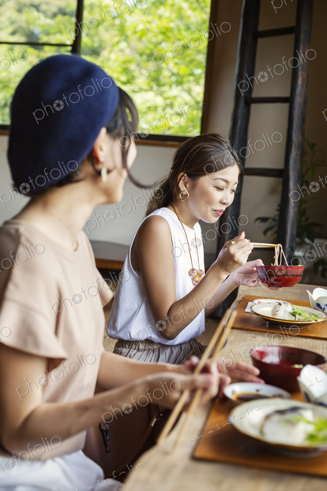 Two Japanese women sitting at a table in a Japanese restaurant, eating.