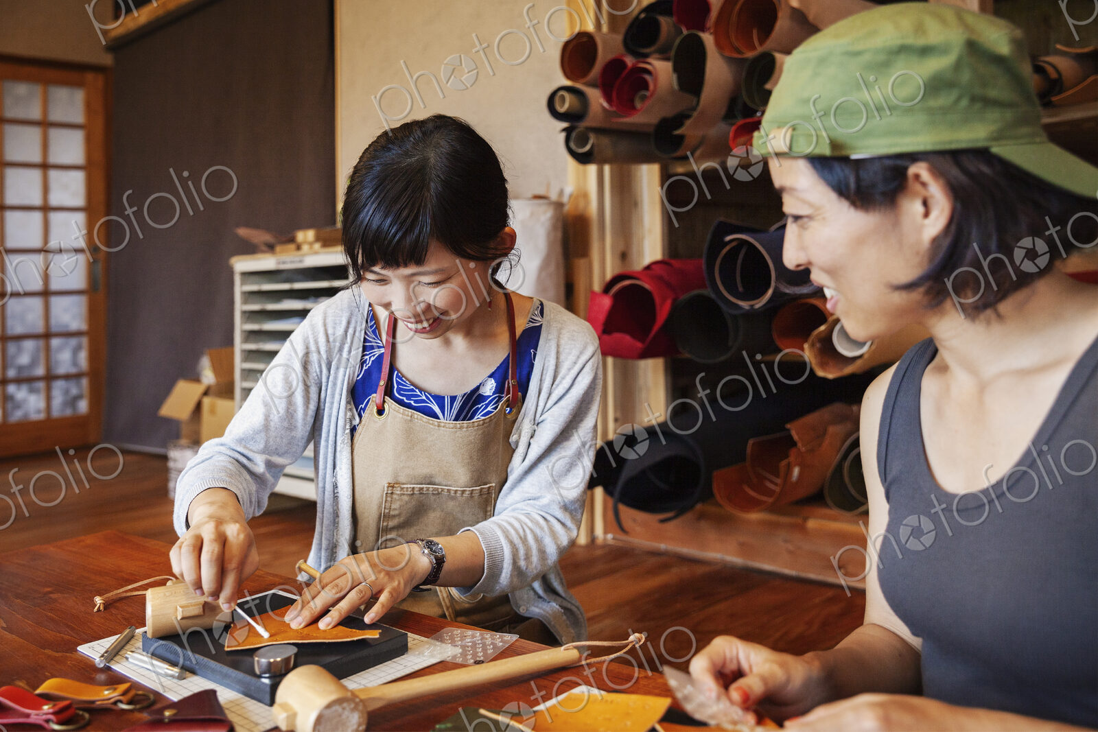 Two Japanese women sitting at a table, working in a leather shop.