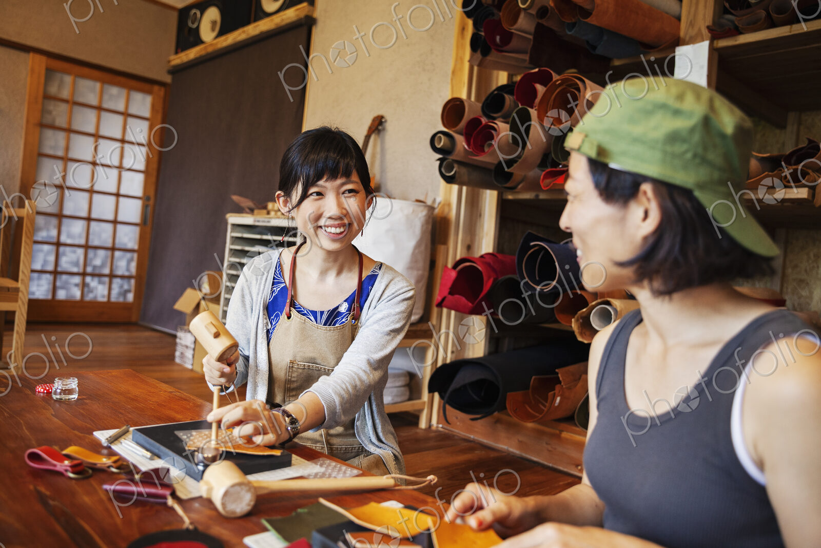 Two Japanese women sitting at a table, working in a leather shop.