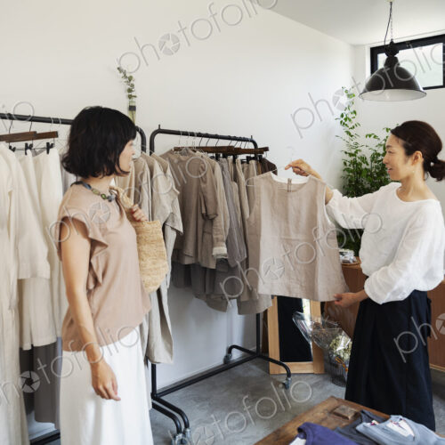 Two Japanese women standing in a small fashion boutique, looking at tops. Two Japanese women standing in a small fashion boutique, looking at tops.