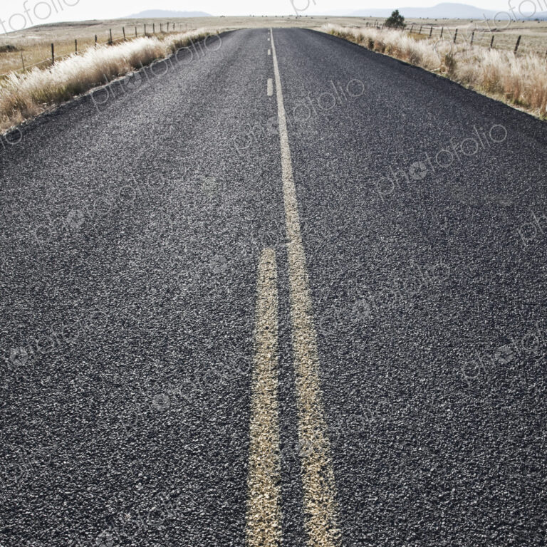 Two Lane Road Between Fenced Fields