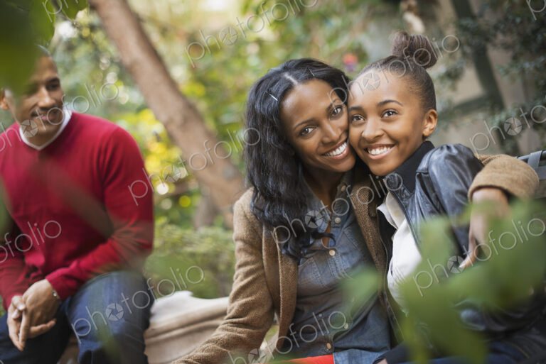 Two adults and a teenage girl, mother and daughter hugging.