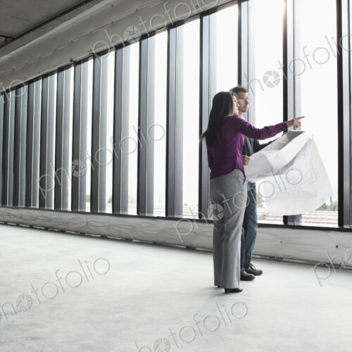 Two architects working on business plans in a new raw business space.