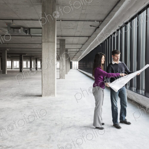 Two architects working on business plans in a new raw business space.