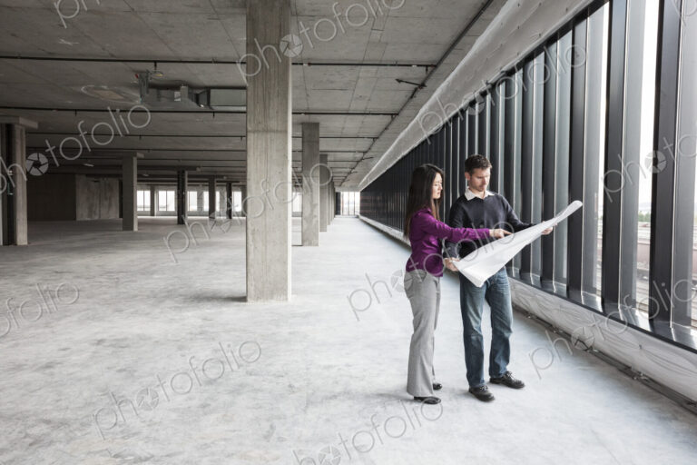 Two architects working on business plans in a new raw business space.