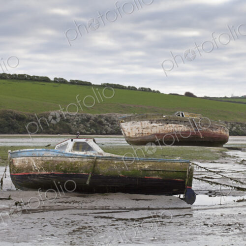 Two boats beached at low tide,with muddy hulls and frayed mooring lines