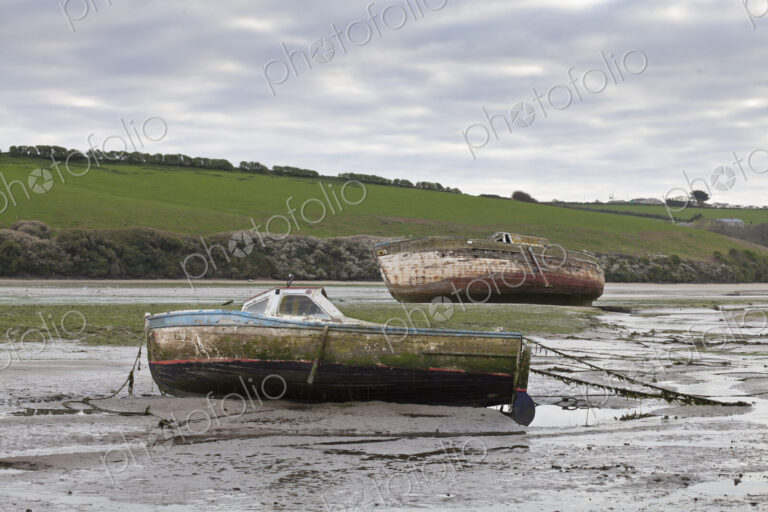 Two boats beached at low tide,with muddy hulls and frayed mooring lines