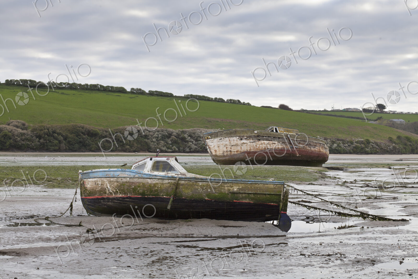 Two boats beached at low tide,with muddy hulls and frayed mooring lines