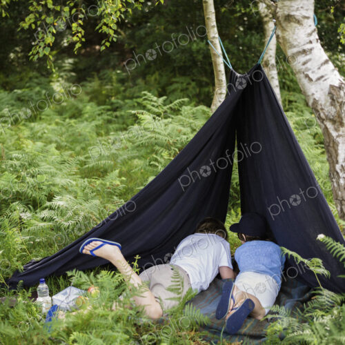 Two boys camping in the New Forest lying under a canvas shelter. Two boys camping in the New Forest lying under a canvas shelter.