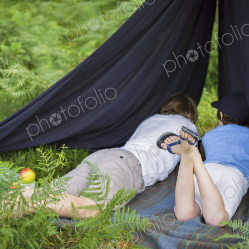 Two boys camping in the New Forest lying under a canvas shelter. Two boys camping in the New Forest lying under a canvas shelter.