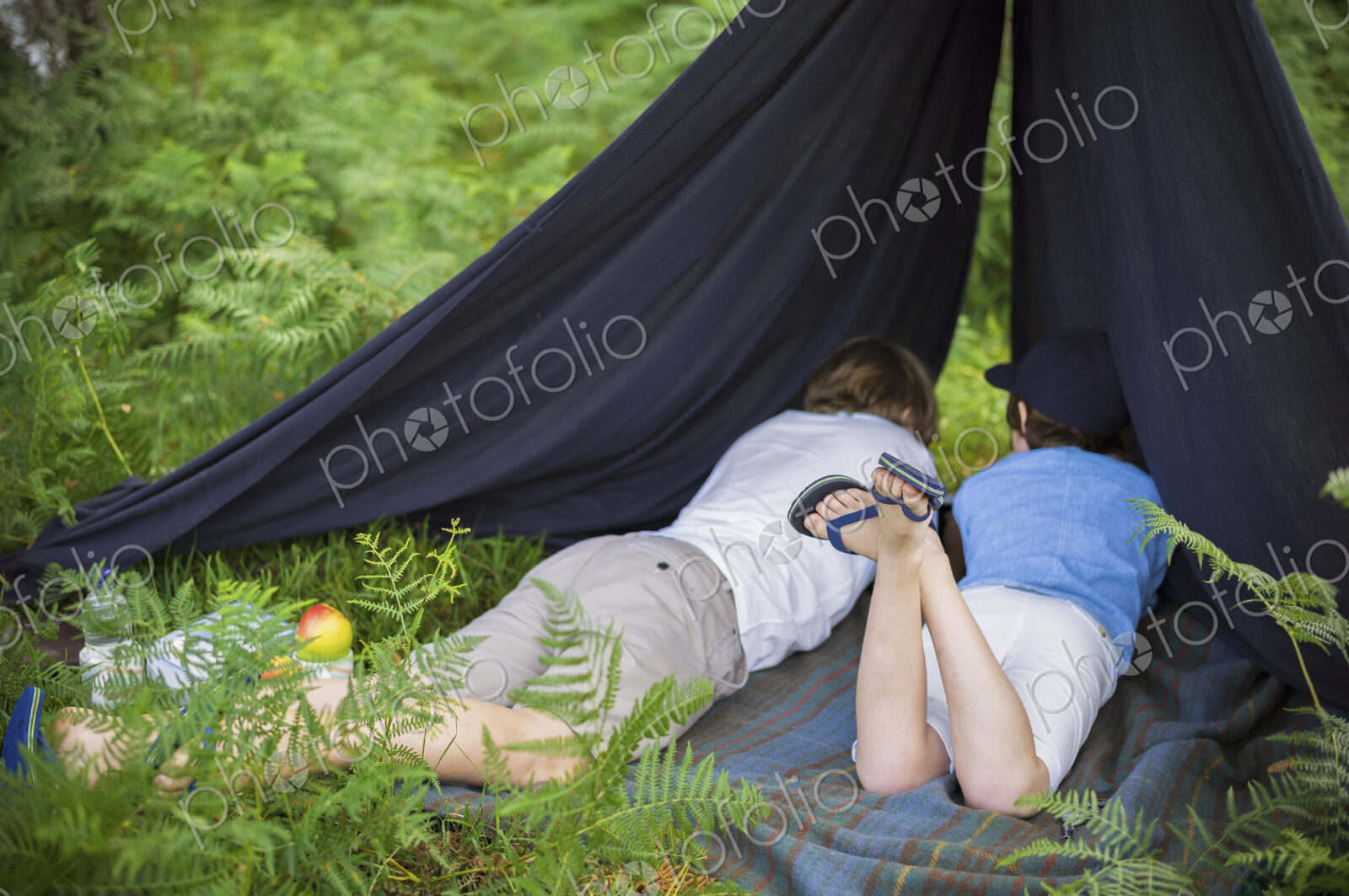 Two boys camping in the New Forest lying under a canvas shelter.