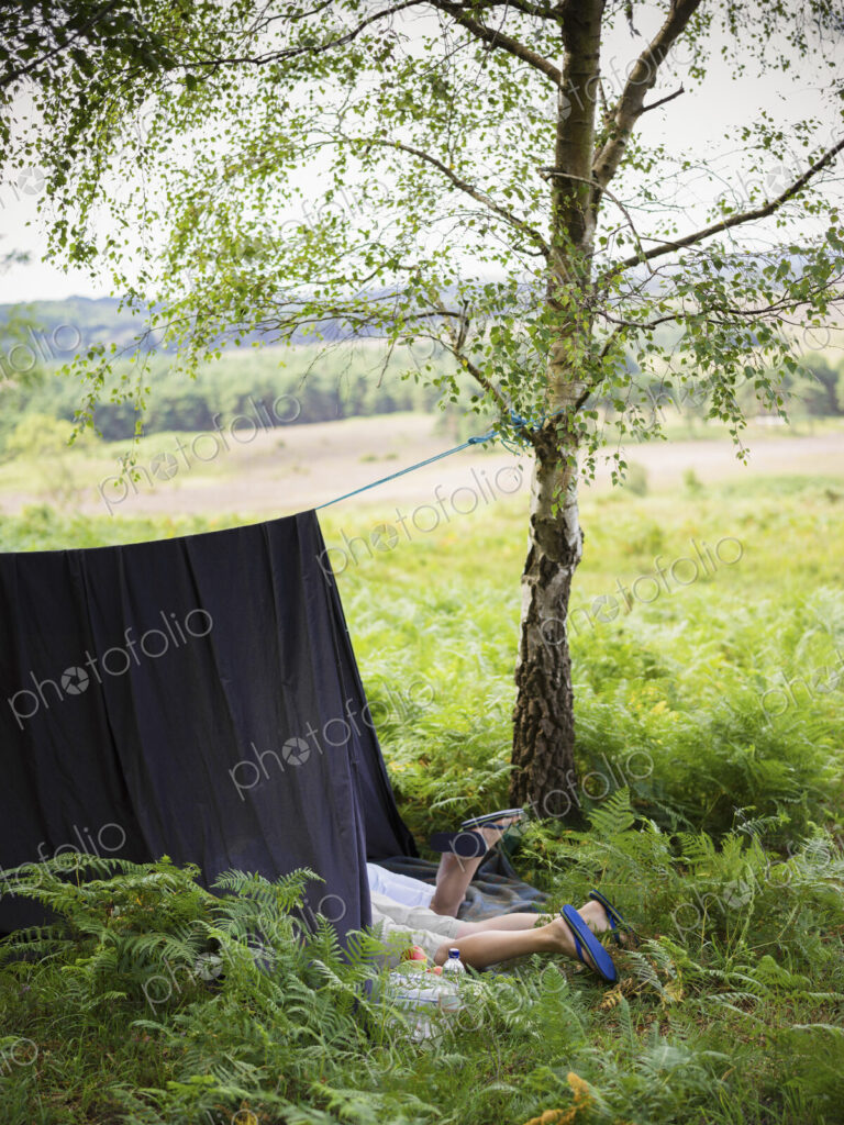 Two boys camping in the New Forest lying under a canvas shelter.
