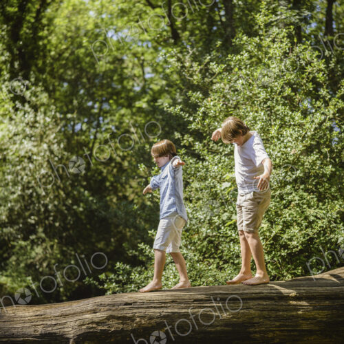 Two boys camping in the New Forest. Walking along a log above the water, balancing… Two boys camping in the New Forest. Walking along a log above the water, balancing…