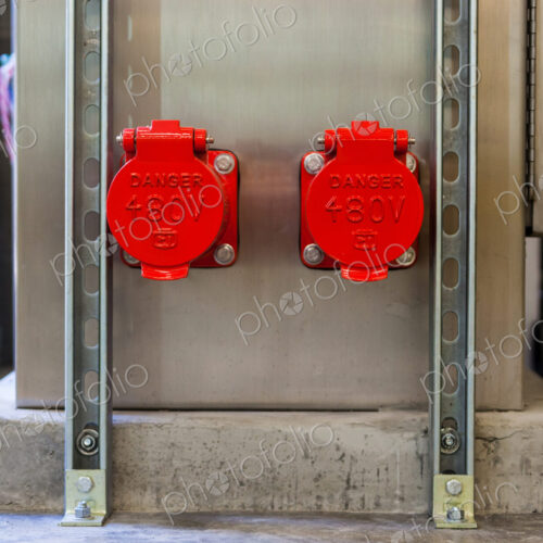 Two bright red plastic covers, caps covering electricity power points on a wall, sign… Two bright red plastic covers, caps covering electricity power points on a wall, sign…