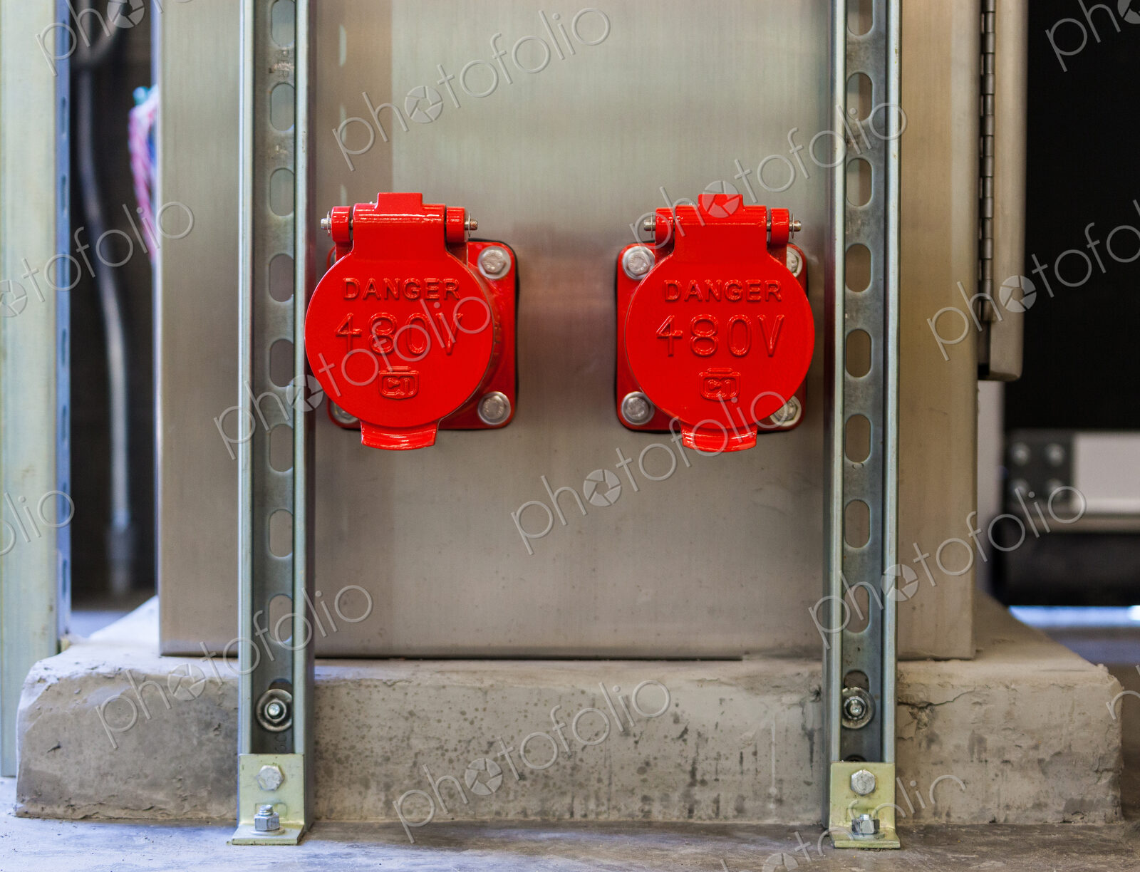 Two bright red plastic covers, caps covering electricity power points on a wall, sign…