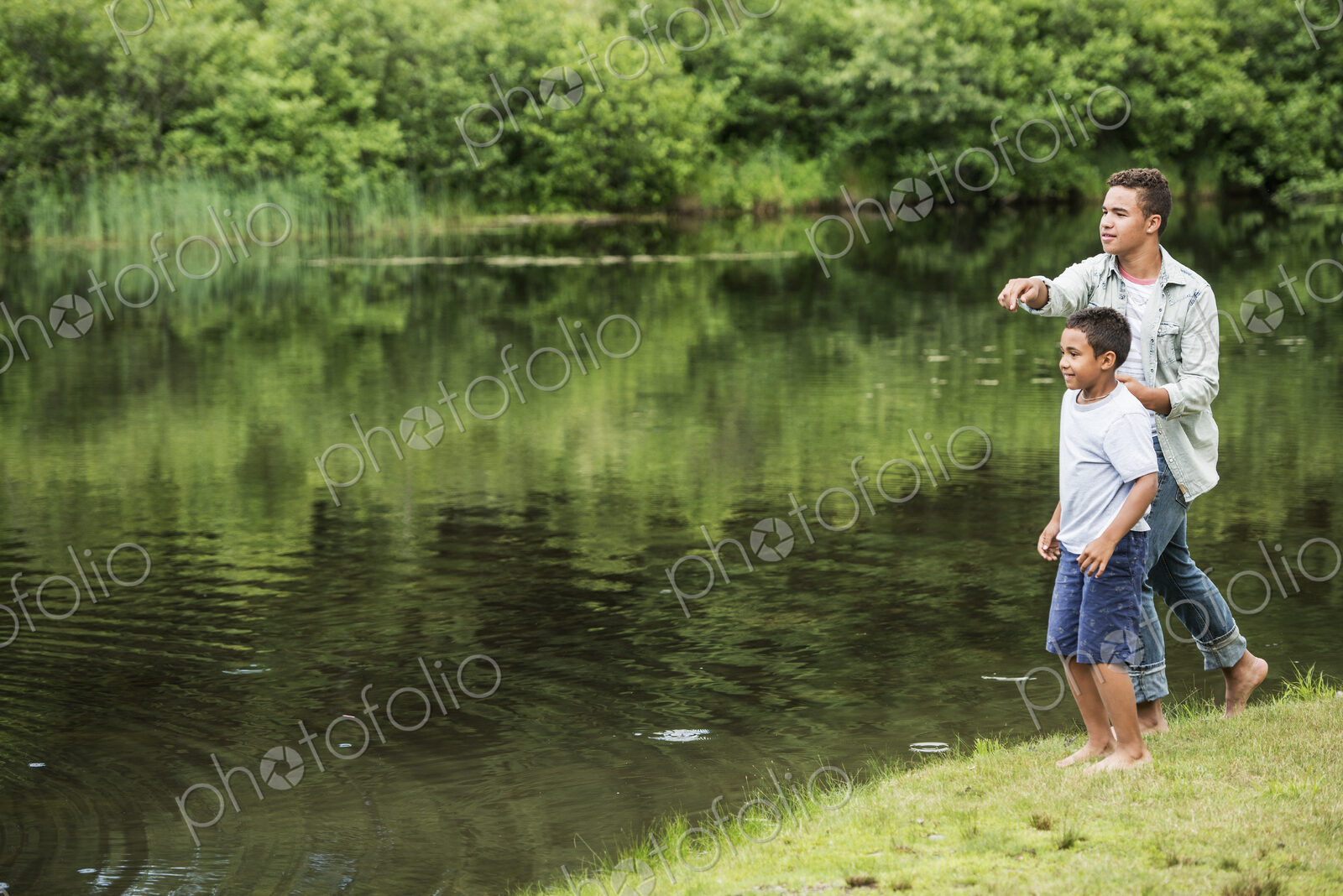 Two brothers playing by a lake.