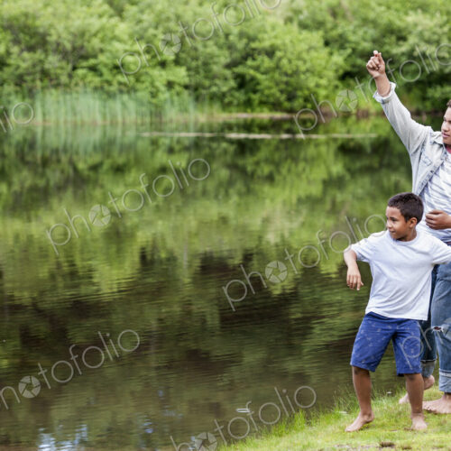 Two brothers playing by a lake.