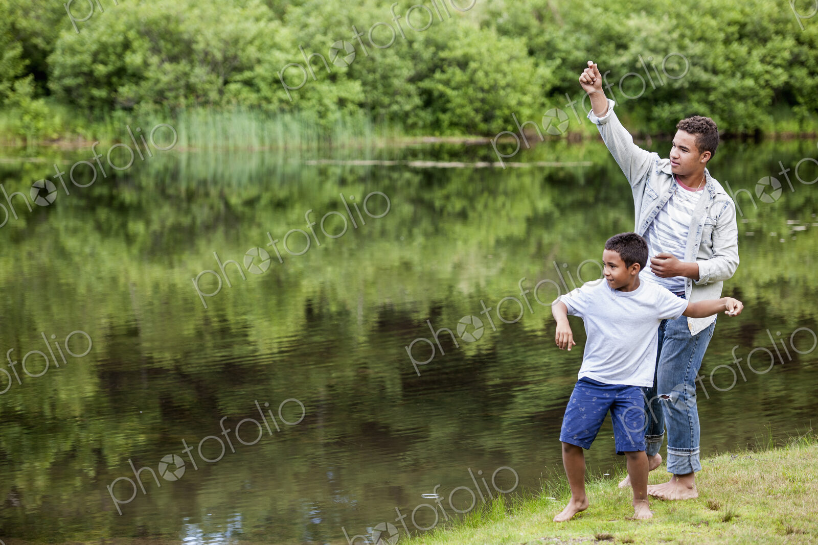 Two brothers playing by a lake.
