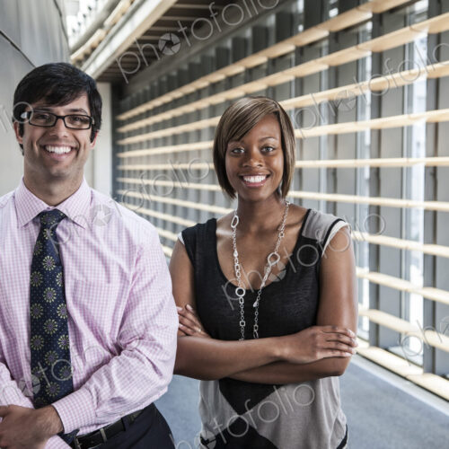 Two business people, a man and woman in the lobby of a large office building. Two business people, a man and woman in the lobby of a large office building.