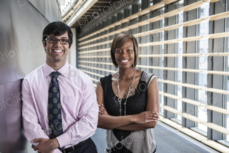 Two business people, a man and woman in the lobby of a large office building.