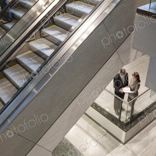 Two business people going over a report while standing next to a convention center… Two business people going over a report while standing next to a convention center…