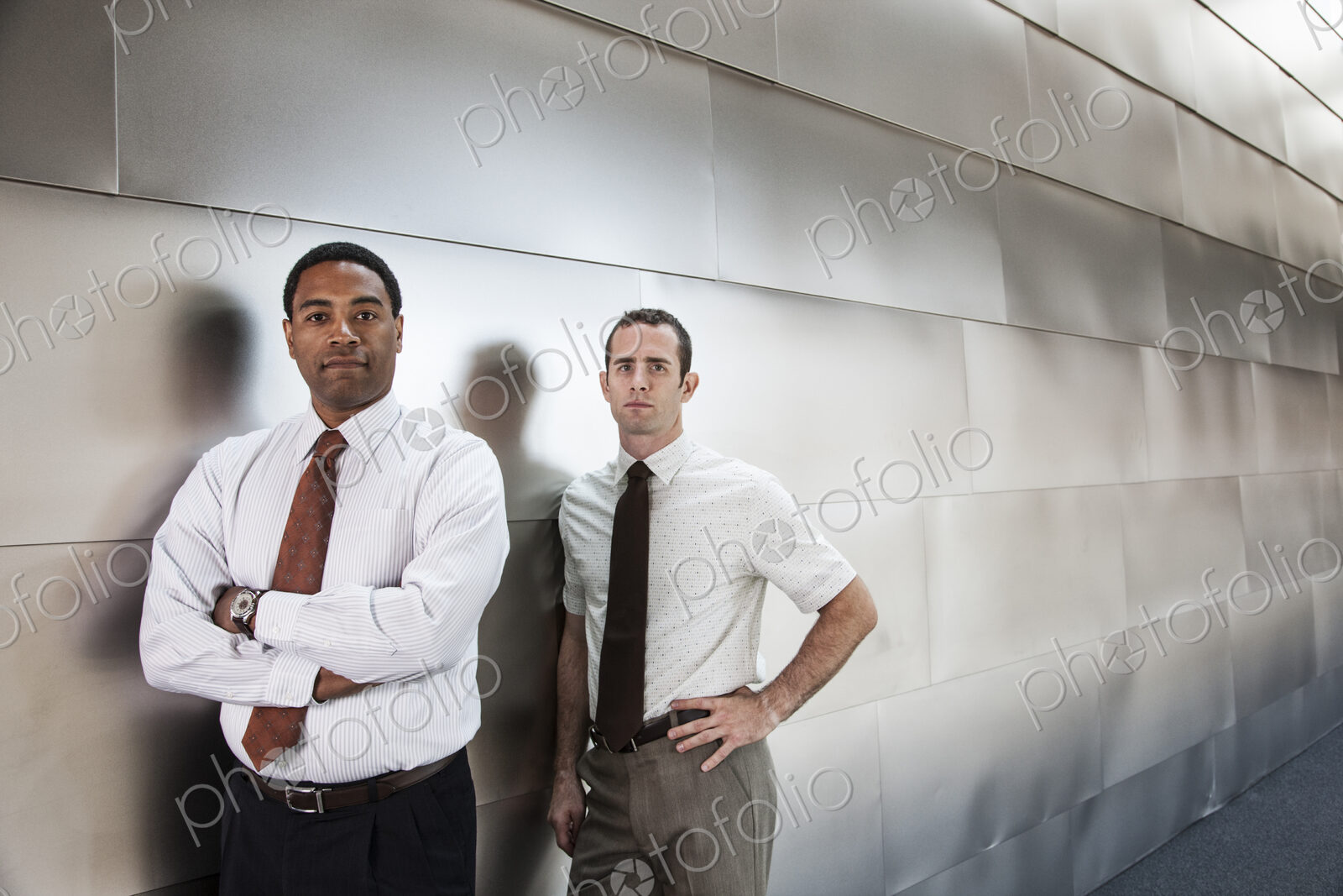 Two businessmen standing in an office corridor.