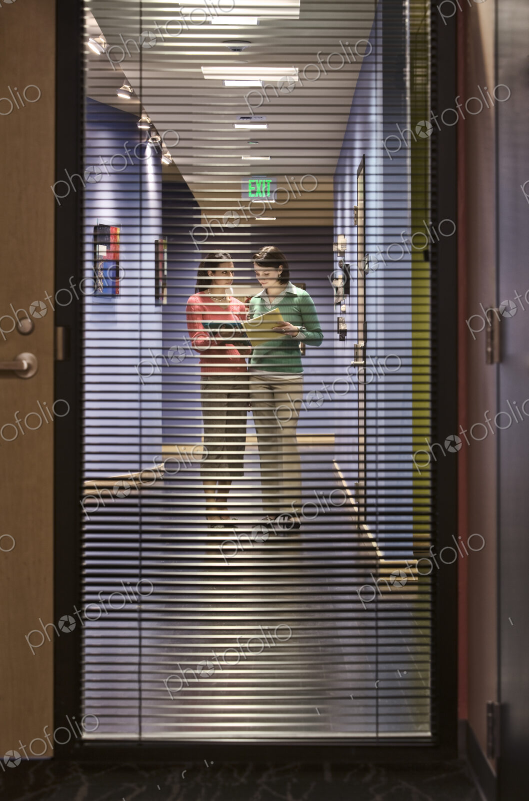 Two businesswomen walking down a hallway together.