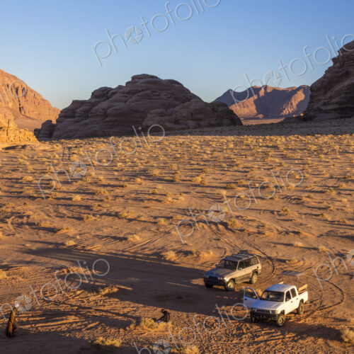 Two cars parked in desert landscape with rocks and mountains. Two cars parked in desert landscape with rocks and mountains.