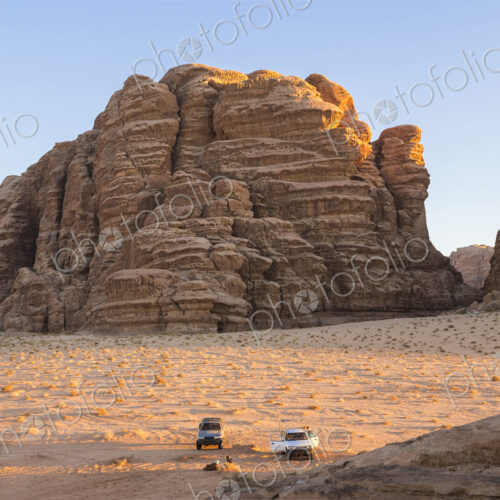 Two cars parked in desert landscape with rocks and mountains. Two cars parked in desert landscape with rocks and mountains.