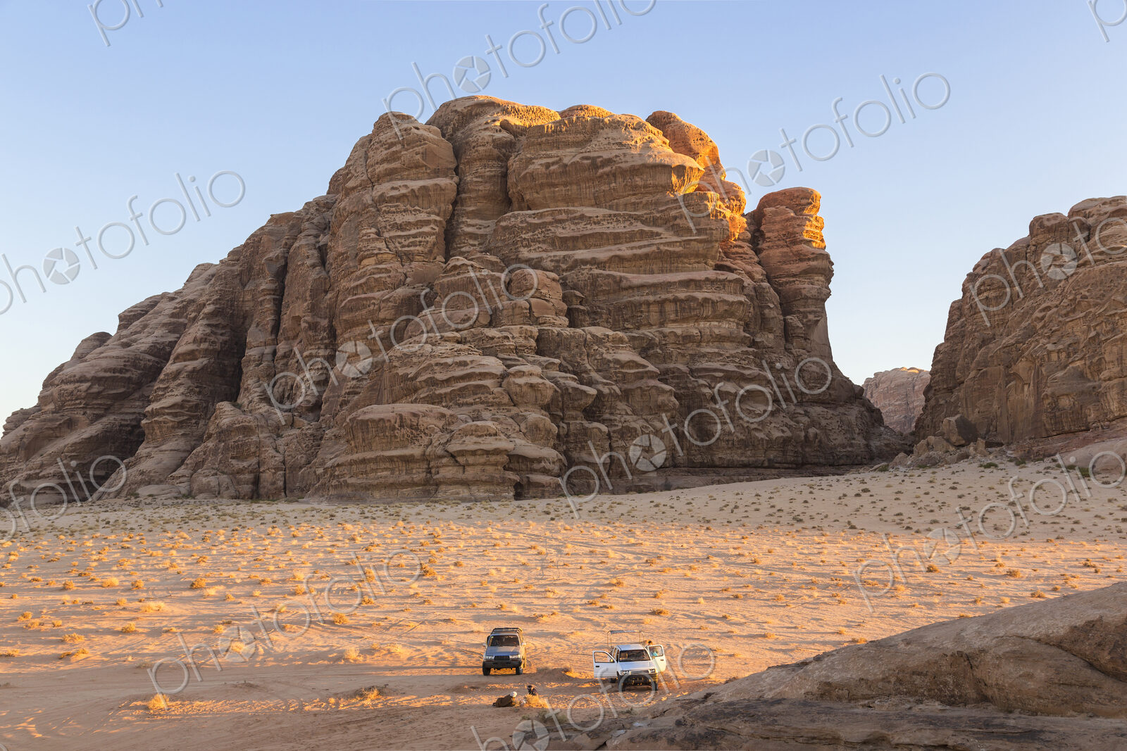 Two cars parked in desert landscape with rocks and mountains.