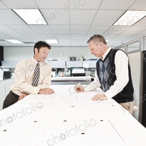 Two caucasian businessmen working on plans for a new office space. Two caucasian businessmen working on plans for a new office space.