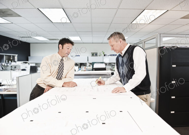Two caucasian businessmen working on plans for a new office space.
