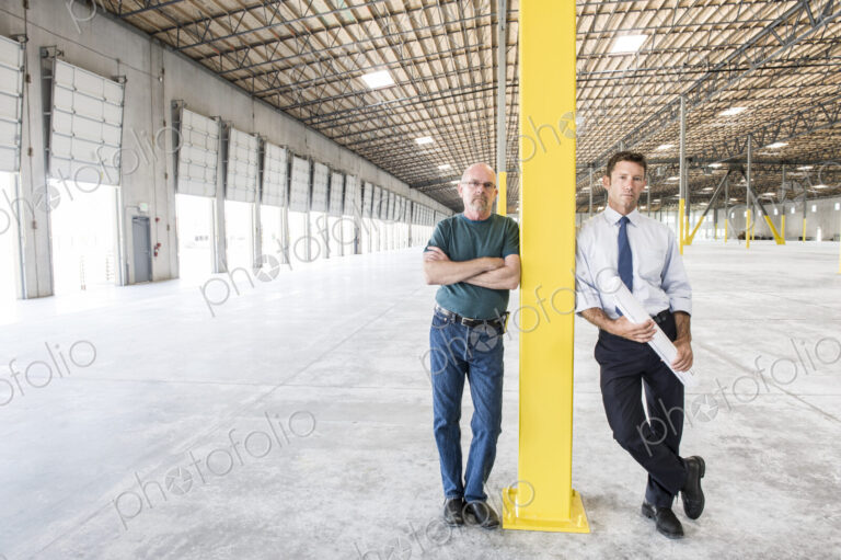 Two caucasian men standing in front of loading dock doors in a new warhouse interior.
