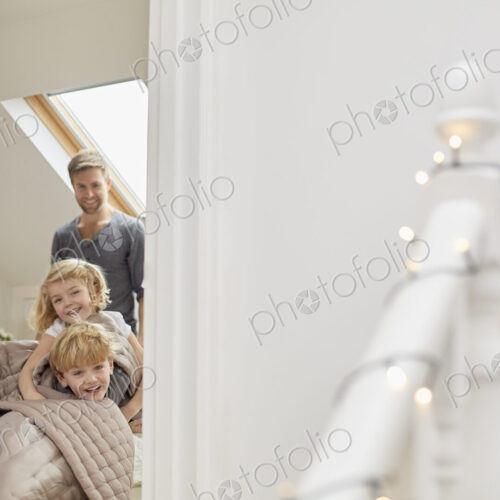 Two children and a man in a bedroom looking excitedly through the door. Two children and a man in a bedroom looking excitedly through the door.