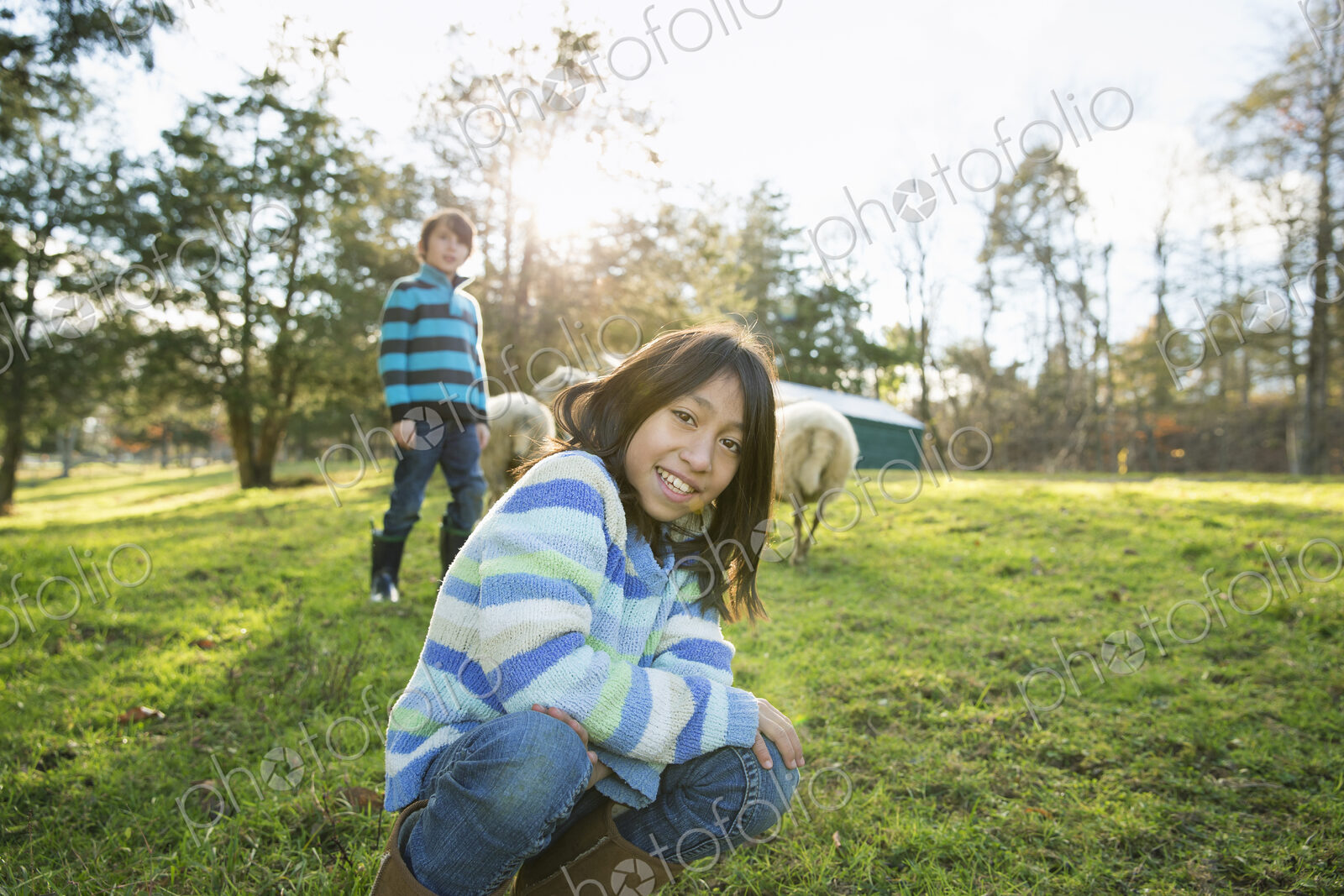 Two children at an animal sanctuary, in an animal enclosure with a group of sheep.