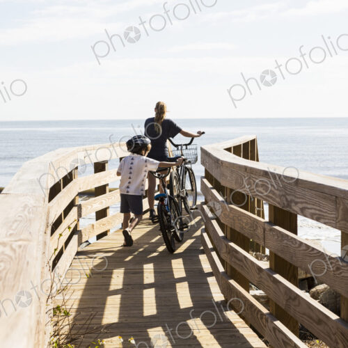 Two children, brother and sister on wooden bridge with bikes