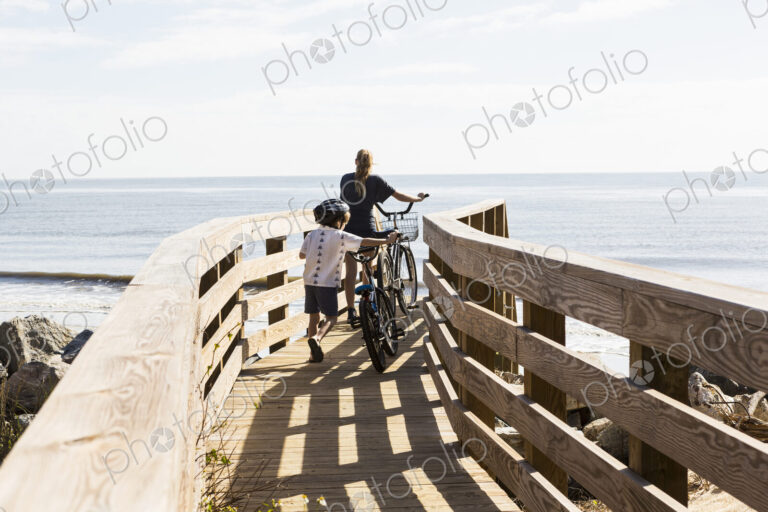 Two children, brother and sister on wooden bridge with bikes