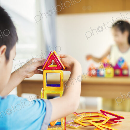 Two children building using geometric shapes.