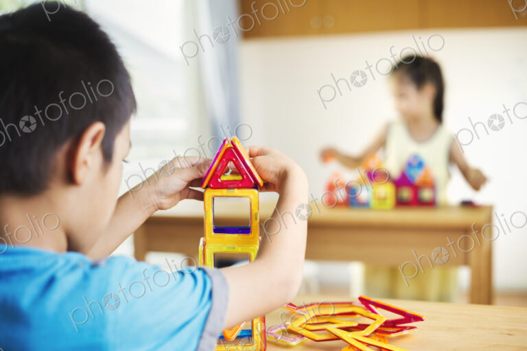 Two children building using geometric shapes.