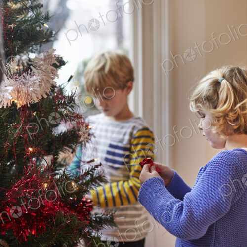 Two children decorating a Christmas Tree in a family home.