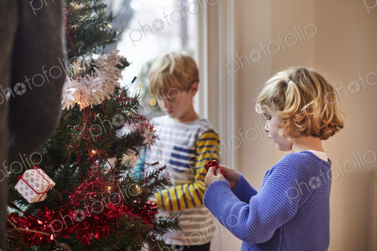 Two children decorating a Christmas Tree in a family home.