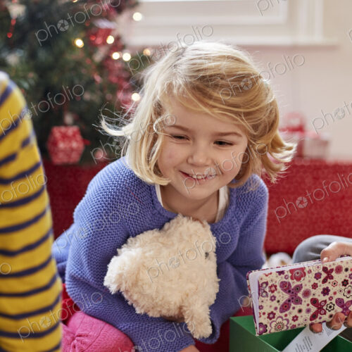 Two children on Christmas Day finding and unwrapping presents at home.