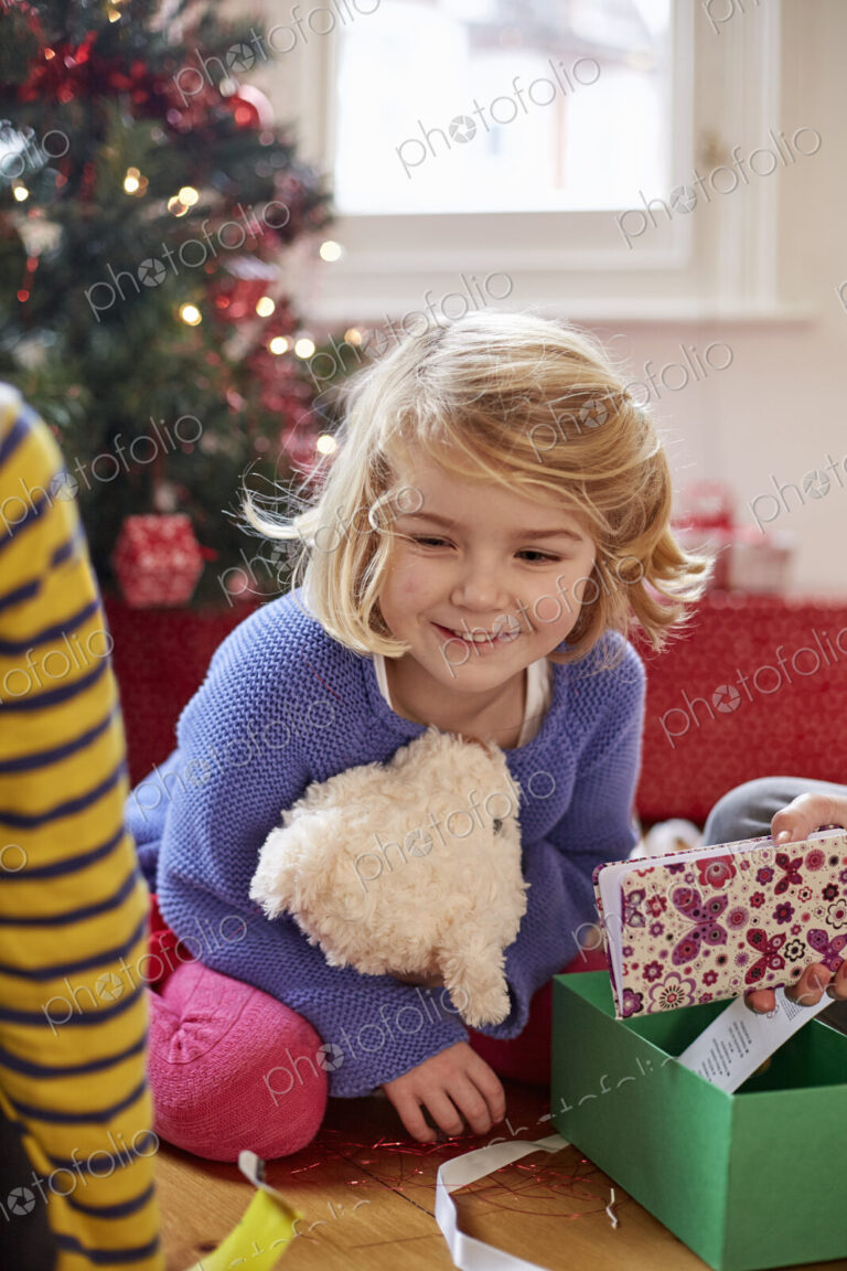 Two children on Christmas Day finding and unwrapping presents at home.