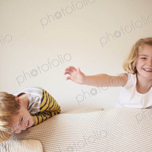 Two children playing behind a sofa, a boy and girl laughing. Two children playing behind a sofa, a boy and girl laughing.