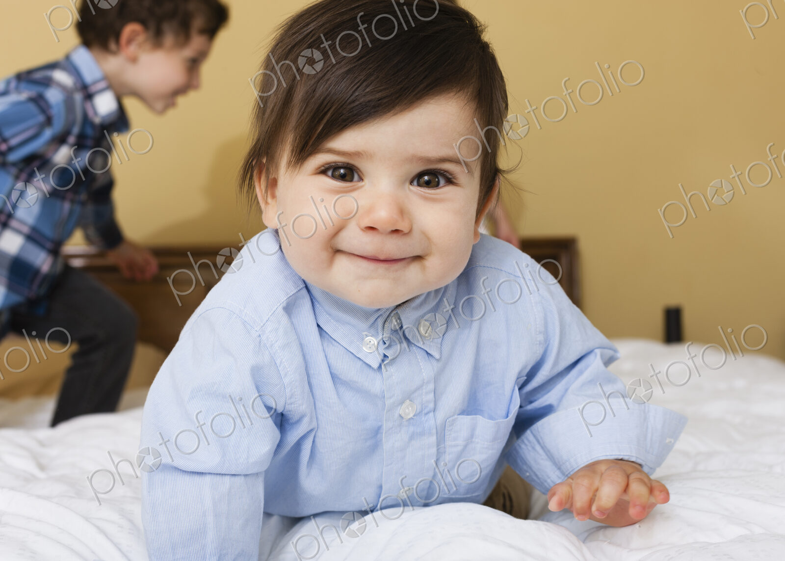 Two children playing on a bed.